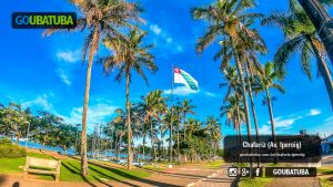 Palmeiras, ciclovia e a bandeira de Ubatuba hasteada no Chafariz da orla da Praia do Cruzeiro em Ubatuba
